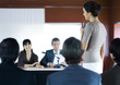 Businesspeople in seminar, one woman standing with microphone