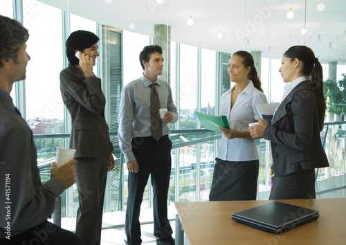 Photo: Business colleagues standing with cups of coffee, chatting Business colleagues standing with cups of coffee, chatting