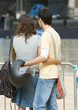 Teenagers standing with arms around each other's waists next to barrier