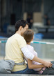 Teenage couple sitting outdoors, girl leaning against boy