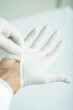 Doctor putting on latex gloves, close-up