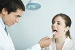 Doctor holding down woman's tongue with tongue depressor