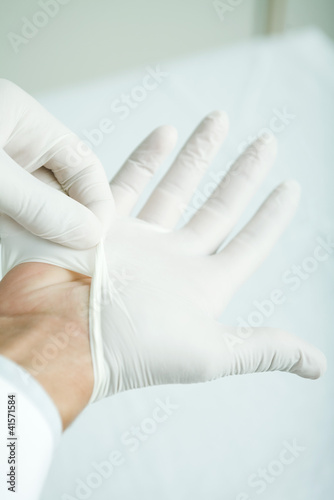 Photo: Doctor putting on latex gloves, close-up Doctor putting on latex gloves, close-up
