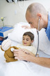 Photo : Boy lying in hospital bed, doctor holding stethoscope to stuffed monkey Boy lying in hospital bed, doctor holding stethoscope to stuffed monkey