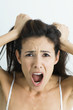 Woman pulling hair and screaming at camera, portrait