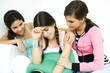 Three young female friends sitting on sofa, two comforting the other