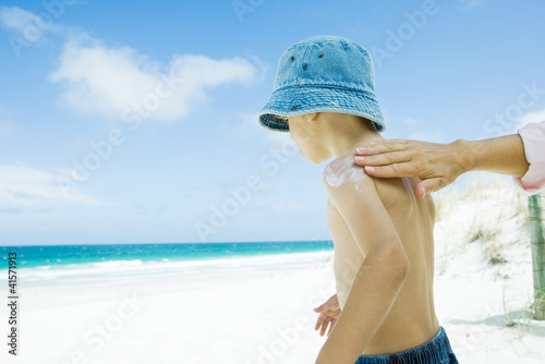 Foto: Mother putting sunscreen on child at beach Mother putting sunscreen on child at beach