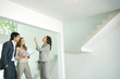 Female real estate agent showing house to young couple, pointing to ceiling