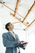Well-dressed man using laptop, inspecting unfinished home interior