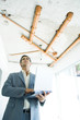Well-dressed man using laptop, inspecting unfinished home interior
