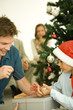 Father and son opening present together by Christmas tree
