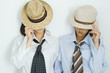 Two young friends pulling hats down over their faces, portrait