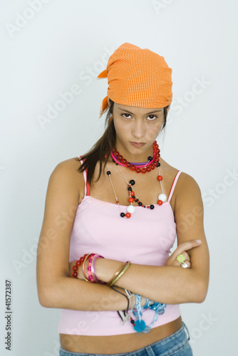 Foto: Teenage girl staring at camera, arms folded, head down, portrait Teenage girl staring at camera, arms folded, head down, portrait