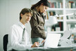 Male and female colleagues at desk, man using laptop computer, woman using phone
