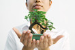 Woman holding bonsai tree out in hands