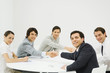 Business associates shaking hands across table, smiling at camera