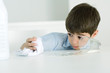 Little boy wiping up spilled milk with towel