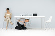 Photo: Man kneeling under desk, connecting tangled wires, woman sitting in chair, looking at hand Man kneeling under desk, connecting tangled wires, woman sitting in chair, looking at hand