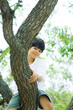 Boy sitting in tree, smiling at camera