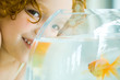 Girl with goldfish bowl, smiling at camera, close-up, cropped