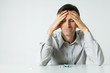 Man sitting next to pills, holding head, eyes closed