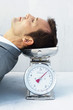 Man resting head on scale, eyes closed