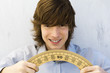 Young man holding protractor in both hands, smiling at camera