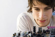 Young man looking down at computer motherboard, close-up