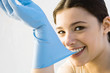 Woman pulling off rubber glove with teeth, smiling at camera