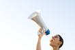 Woman shouting into megaphone, low angle view, cropped