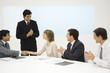 Business associates at conference table, two shaking hands, the others clapping