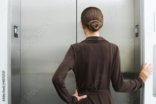 Photo: Well-dressed female waiting for elevator, rear view Well-dressed female waiting for elevator, rear view