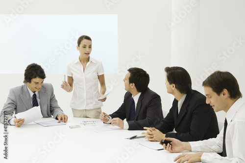 Photo: Businesswoman addressing male colleagues at conference table Businesswoman addressing male colleagues at conference table