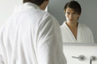 Man looking at himself in mirror, wearing bathrobe, furrowing brow