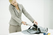 Professional woman using cell phone, putting laptop computer in briefcase, child's toys nearby