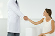 Woman shaking hands with doctor, cropped view
