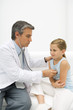 Doctor listening to girl's heart with stethoscope