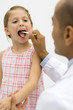 Doctor examining a girl's throat using a tongue depressor