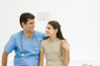 Doctor with arm around teenage girl's shoulder, smiling at each other