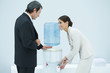 Two professionals chatting beside water cooler, woman filling disposable cup