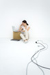 Photo: Young woman sitting on the ground, using laptop computer, loose electric cords nearby Young woman sitting on the ground, using laptop computer, loose electric cords nearby