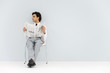 Businessman sitting in chair, holding newspaper, looking away