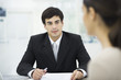 Businessman sitting at desk, listening to female client