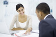 Photo: Professional woman sitting with client at desk, discussing brochure Professional woman sitting with client at desk, discussing brochure