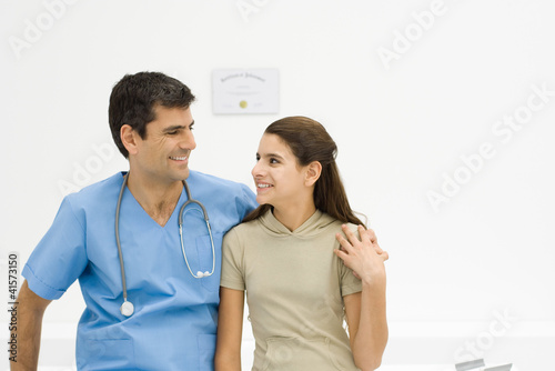 Photo: Doctor with arm around teenage girl's shoulder, smiling at each other Doctor with arm around teenage girl's shoulder, smiling at each other