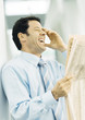 Businessman holding newspaper and laughing
