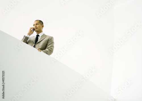 Photo: Businessman using cell phone, low angle view Businessman using cell phone, low angle view