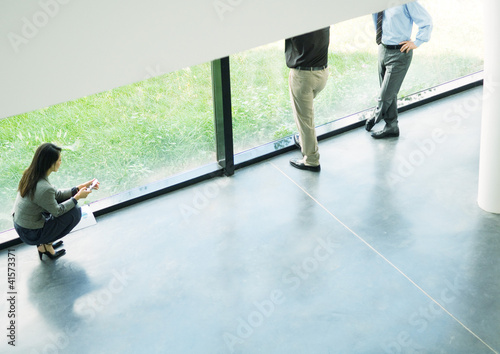 Photo: Business people taking break next to window, high angle view Business people taking break next to window, high angle view