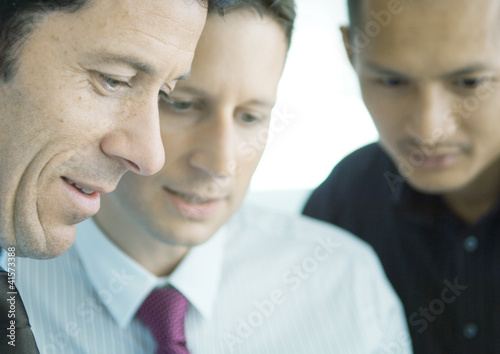 Photo: Three businessmen working together, close-up of faces Three businessmen working together, close-up of faces