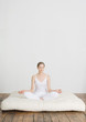Young woman sitting in lotus position on futon mattress